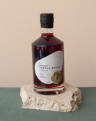 Bottle of Tasmanian Pepper Berry Liqueur on a stone surface with a beige background